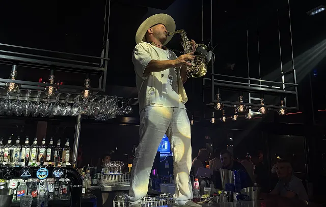 Musicien en costume blanc jouant du saxophone.